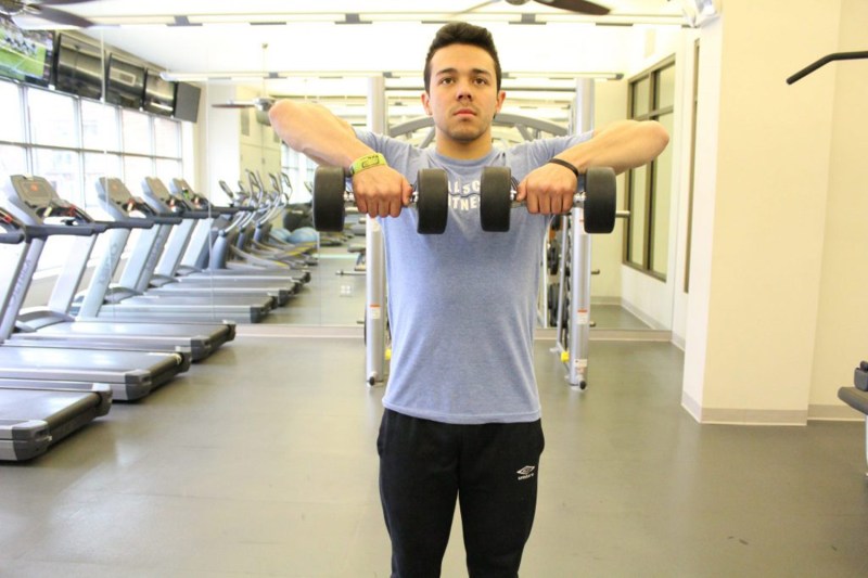 Man holding the dumbbells on each hand in front of his thighs, with his palms facing his body.