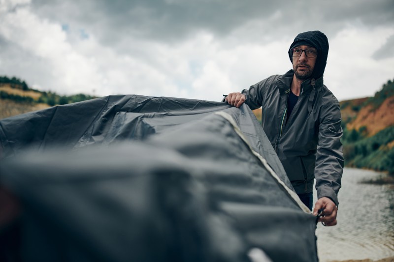 Person covering a tent outside