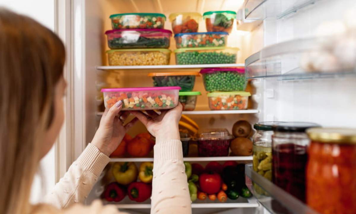 Woman organizing different ingredients in various containers inside the refrigerator.