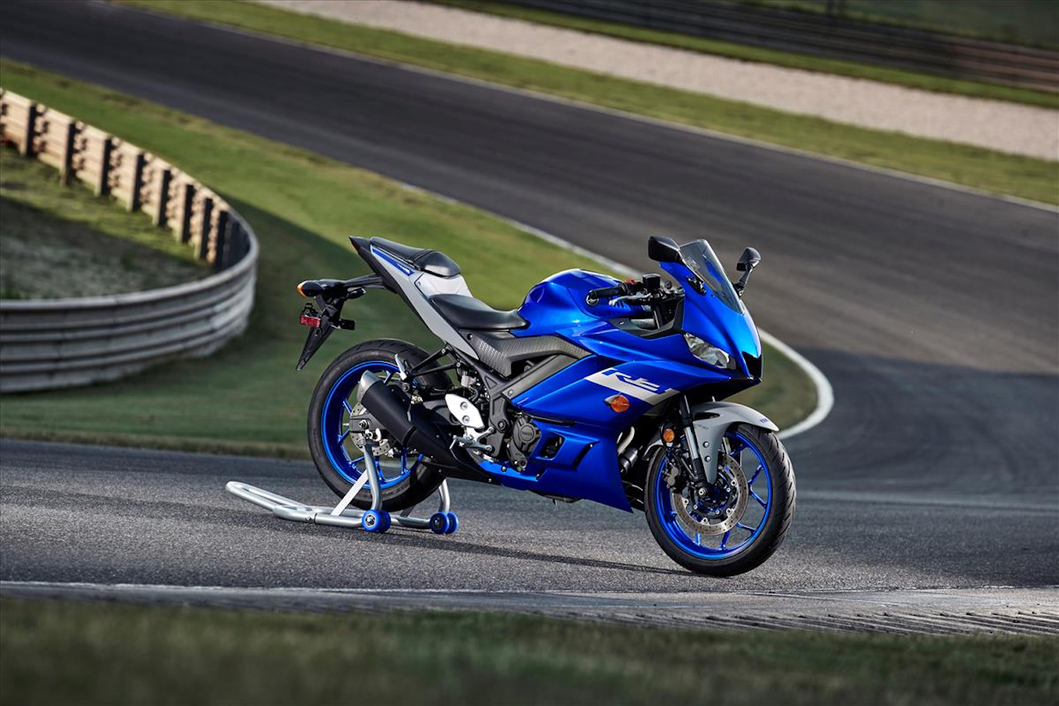 Yamaha YZF-R3 sitting at a corner on a racetrack with a stand.