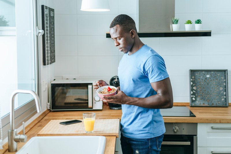 Young man having breakfast in kitchen at home