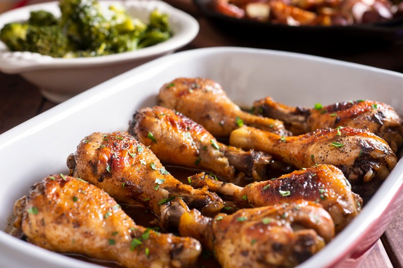 Marinated chicken legs in a baking dish with steamed broccoli and roasted potatoes