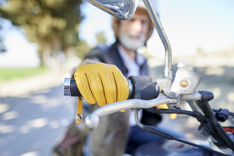 Close-up of hand with yellow gloves on motorcycle handlebar