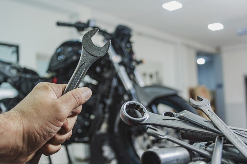 Hand of a mechanic holding a wrench in workshop.