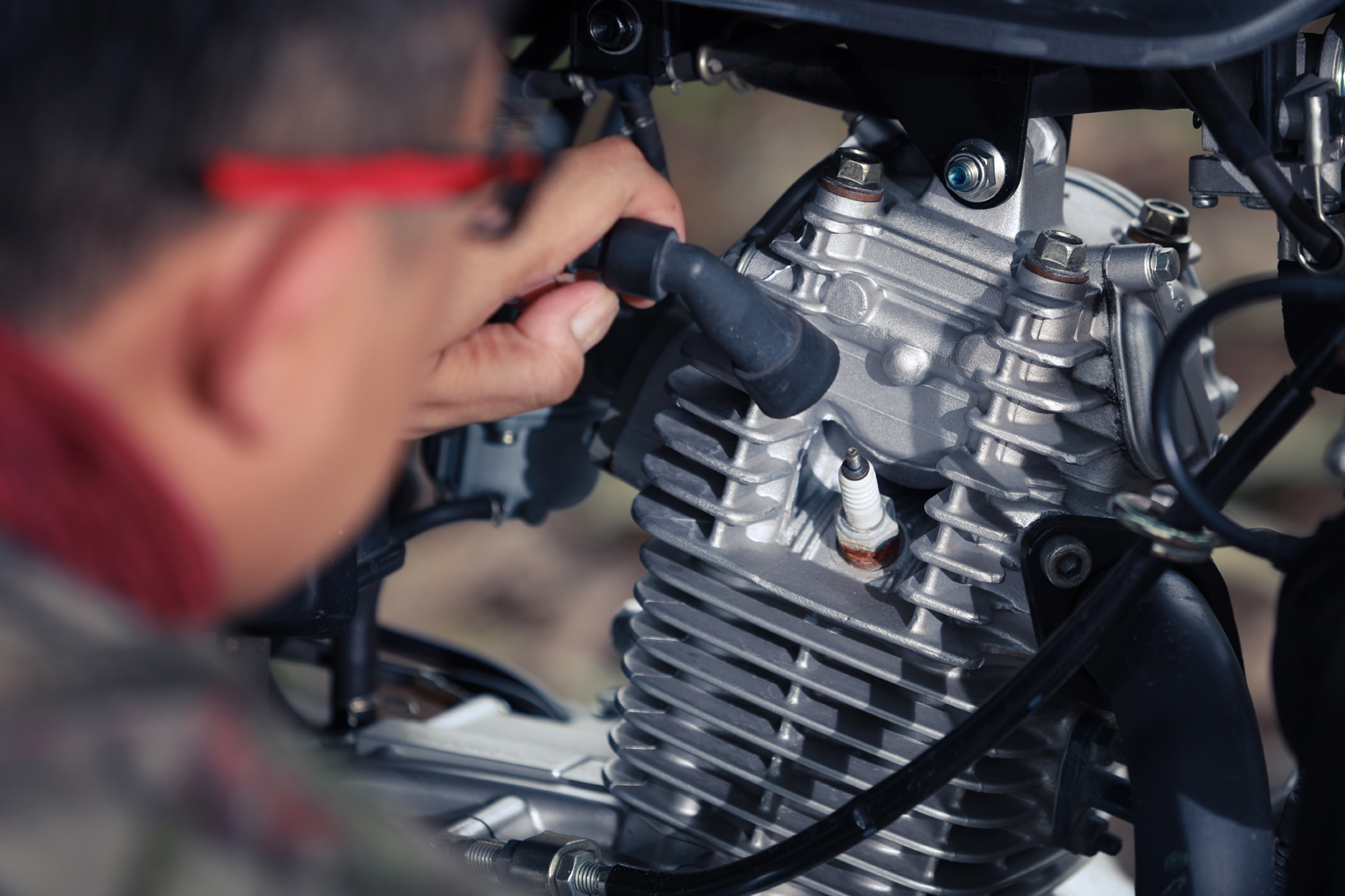 Mechanic man checking a spark plug of vintage motorcycle.