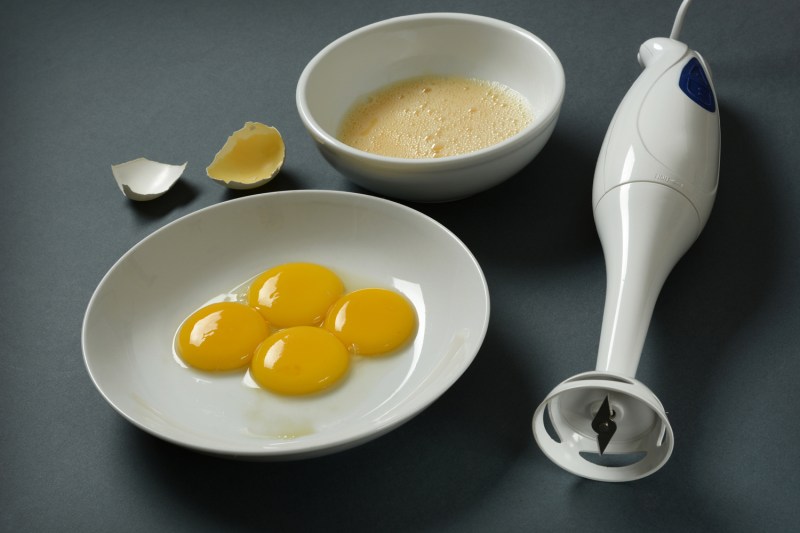 immersion Blender and egg yolks on a plate on the table.