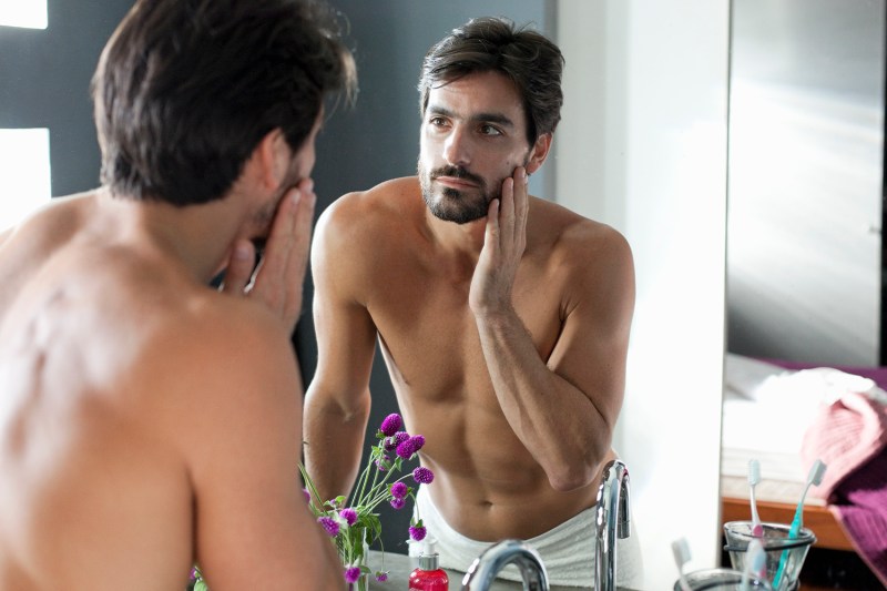 A man looking at himself in bathroom mirror.