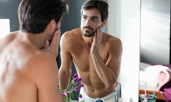 A man looking at himself in bathroom mirror.