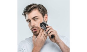 A close-up of a man shaving holding the electric razor to his face