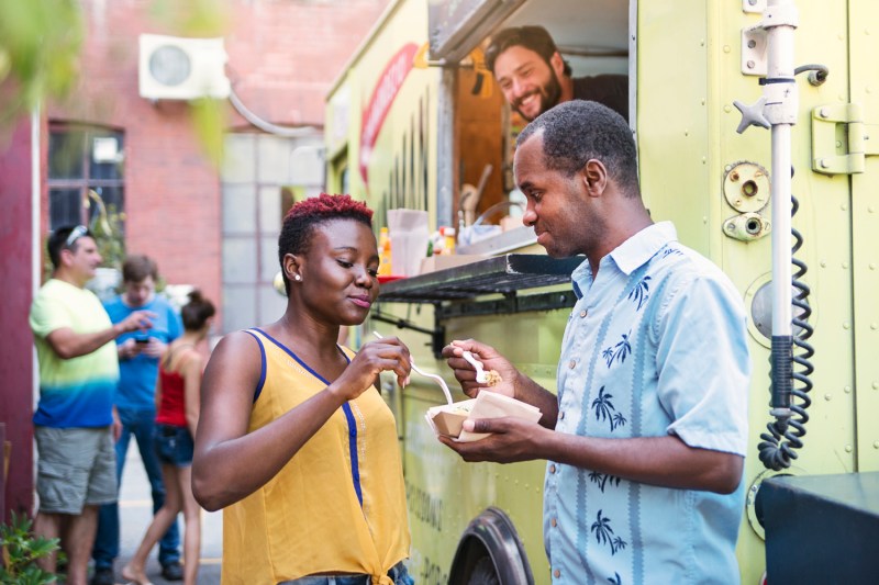 Couple eating lunch near a food truck.