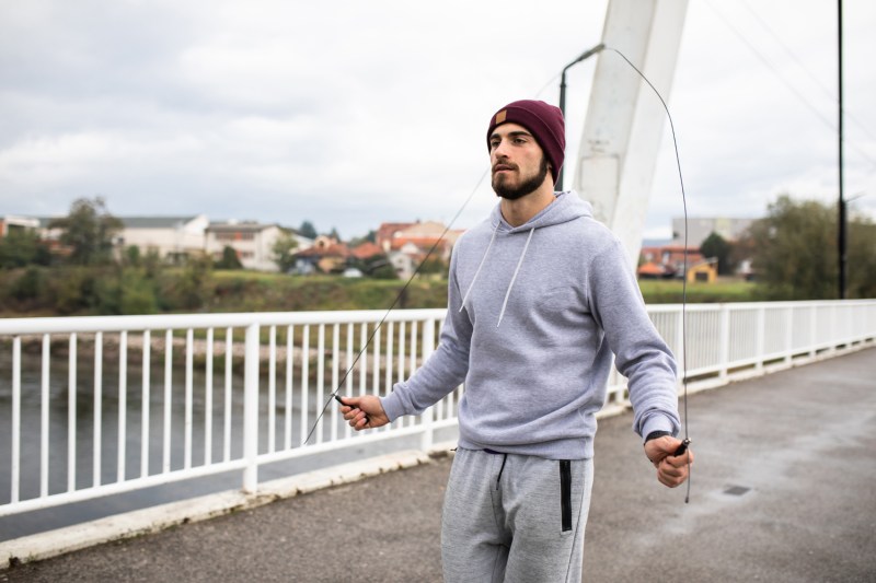 A bearded man skipping rope on a bridge.