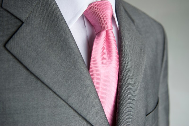 Close-up bright pink necktie makes a colorful contrast to a neutral gray suit on businessman.