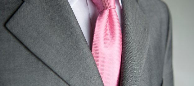 Close-up bright pink necktie makes a colorful contrast to a neutral gray suit on businessman