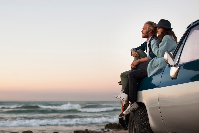 A couple sitting on truck looking at ocean view.