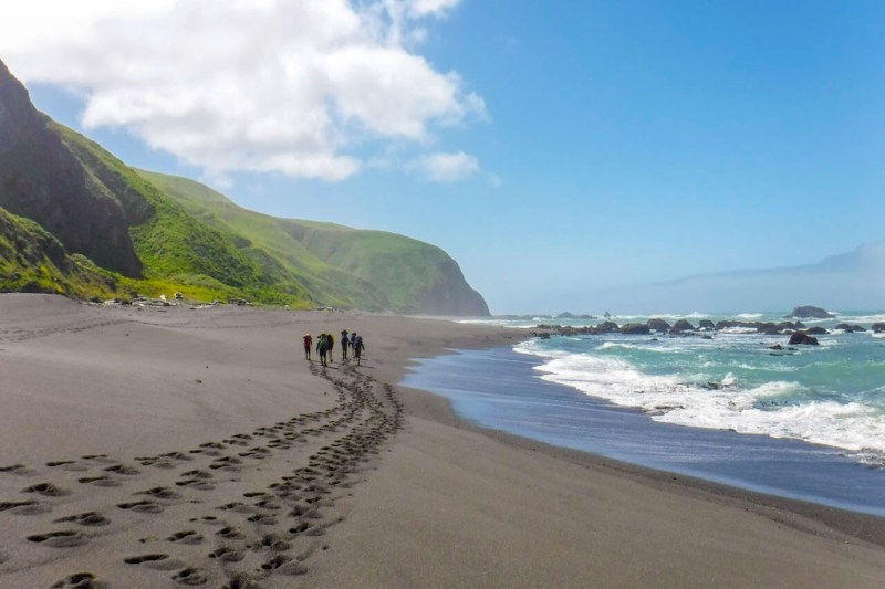 Adventurers leaving footprints on the sand along the shores of California’s Lost Coast. 