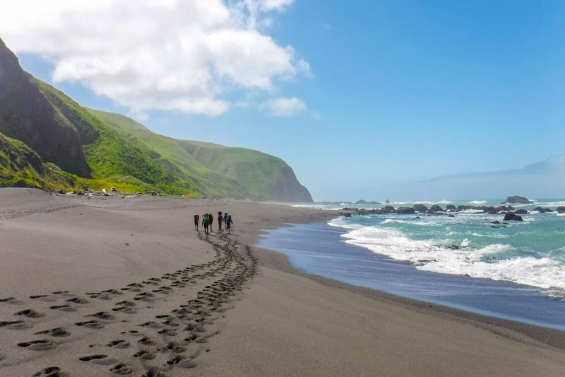 Adventurers leaving footprints on the sand along the shores of California’s Lost Coast.