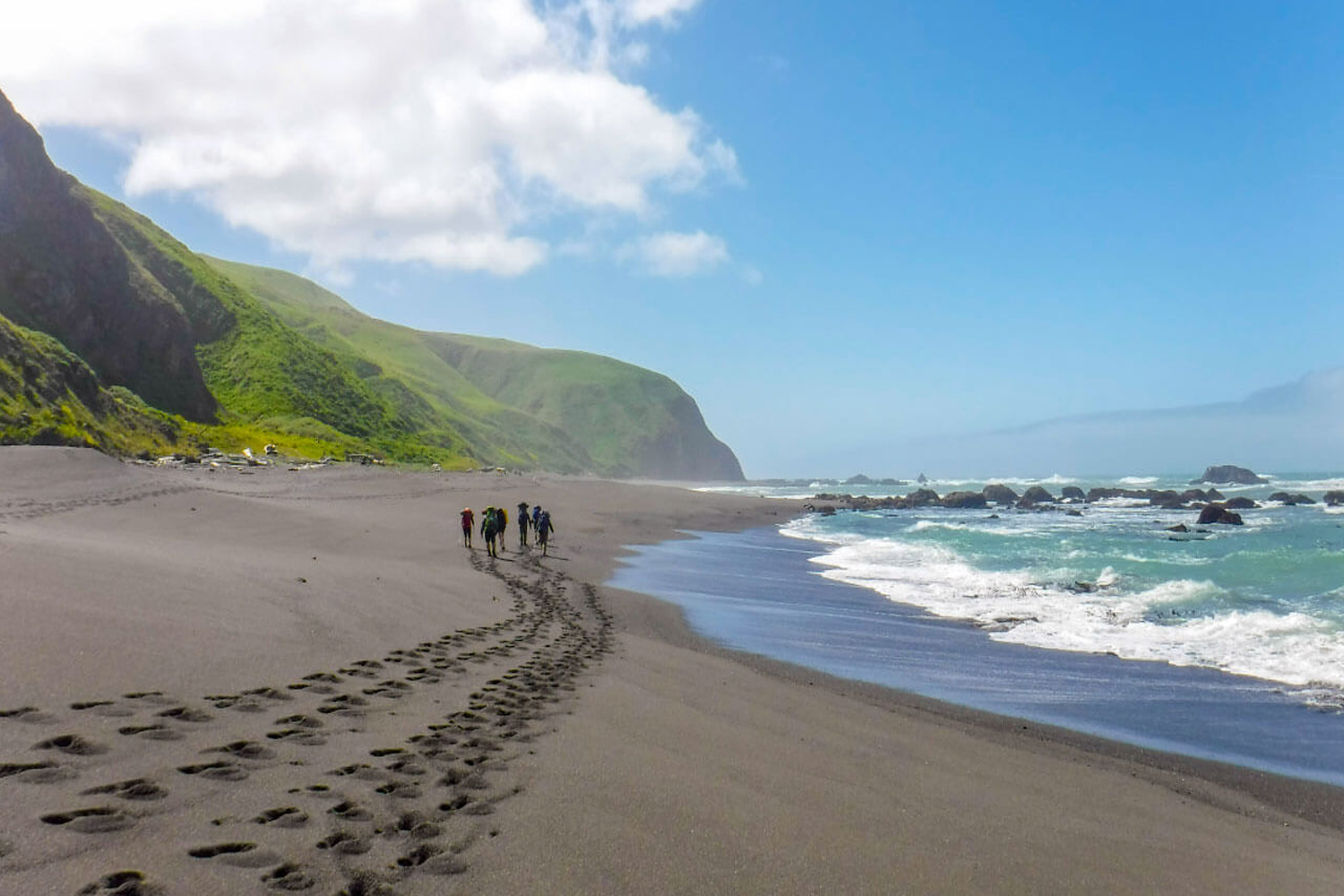 Adventurers leaving footprints on the sand along the shores of California’s Lost Coast.