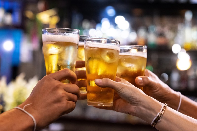 Group of happy friends drinking and toasting beer at brewery bar restaurant.