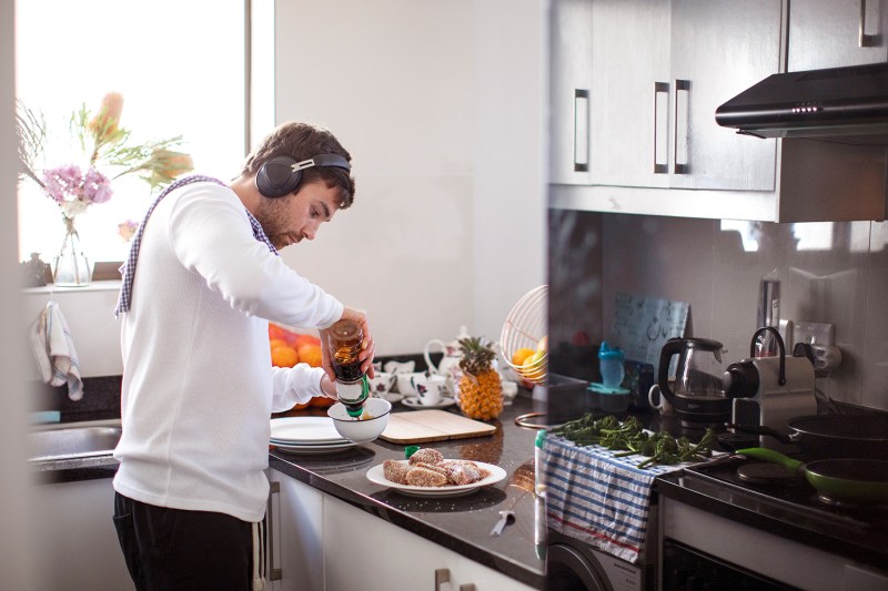 Man wearing headphones cooking in kitchen.