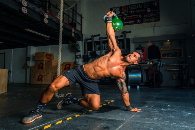 A man doing an oblique exercise with a kettlebell.