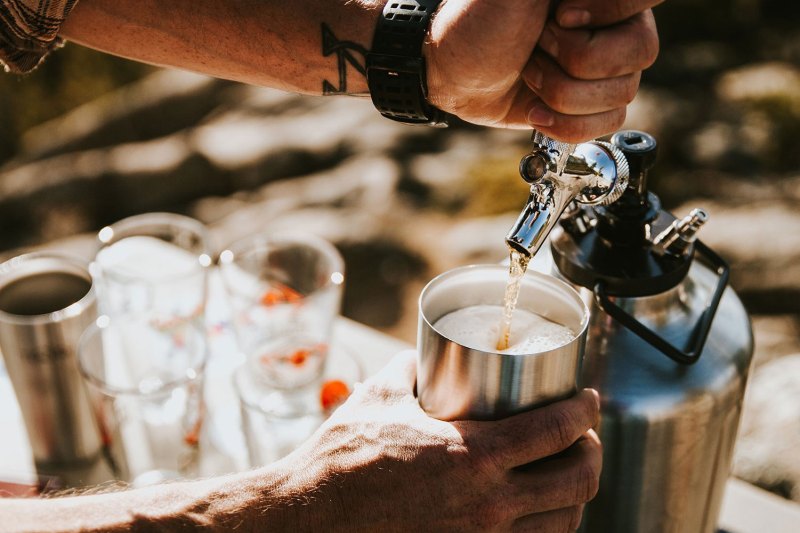 Man pouring a draft beer from a pressurized beer growler.