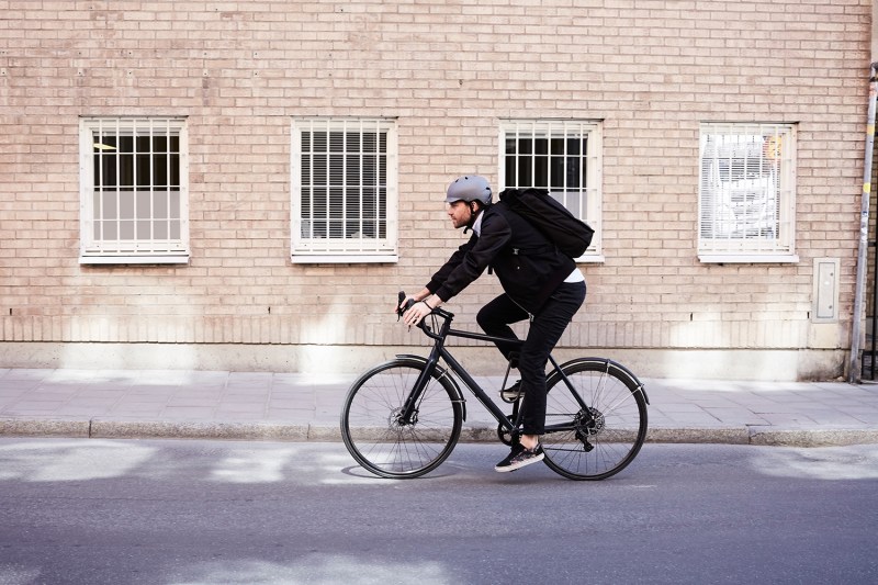 Man riding bicycle with building in background.