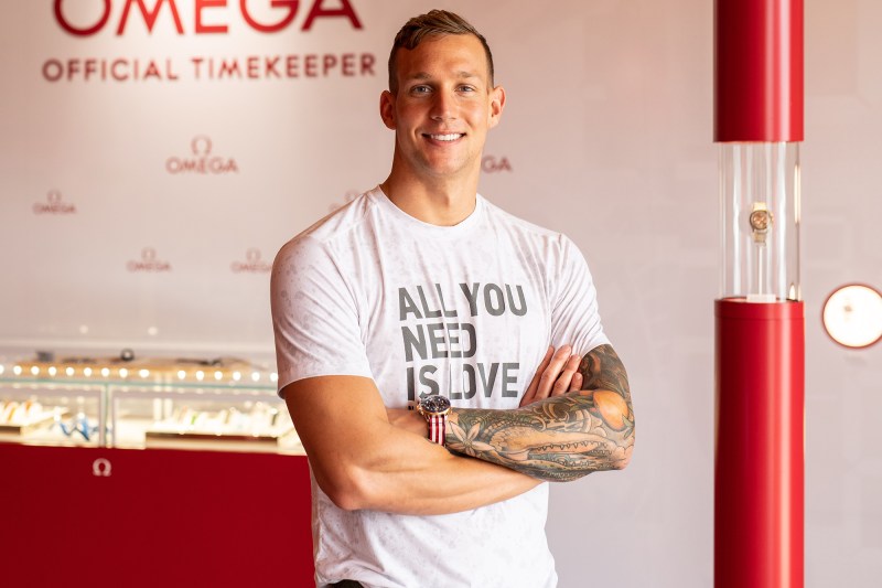 Caeleb Dressel posing with a watch inside an OMEGA store