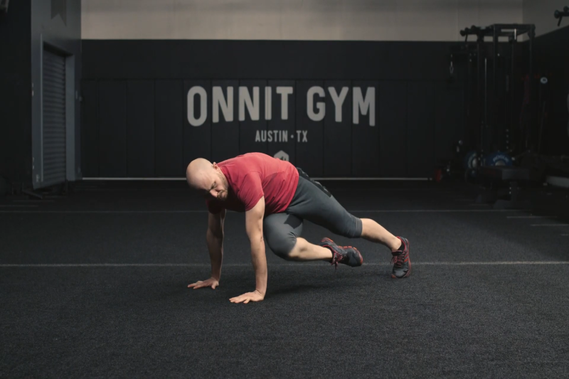 An athlete performing the crossover mountain climbers at the Onnit Gym.
