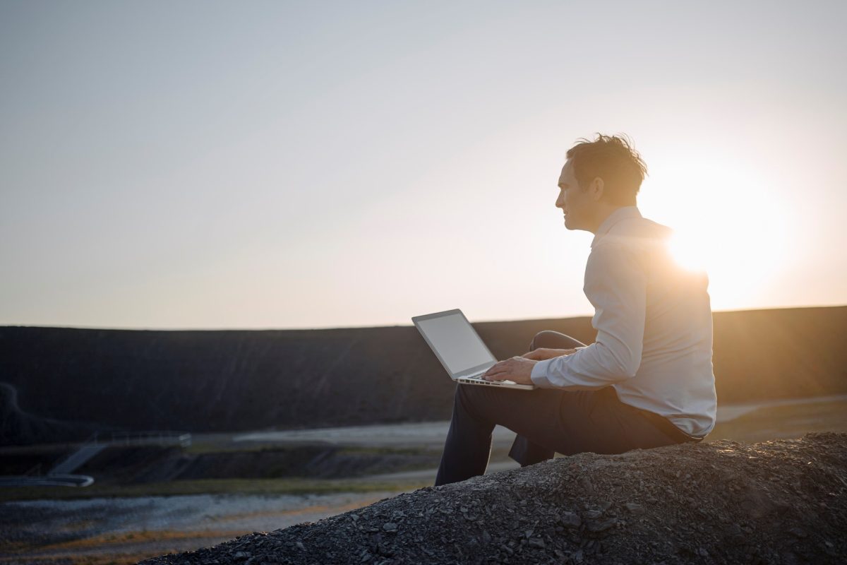 Un homme avec un ordinateur portable sous le coucher du soleil
