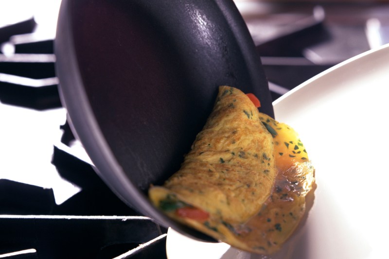 Flipping omelette into plate.