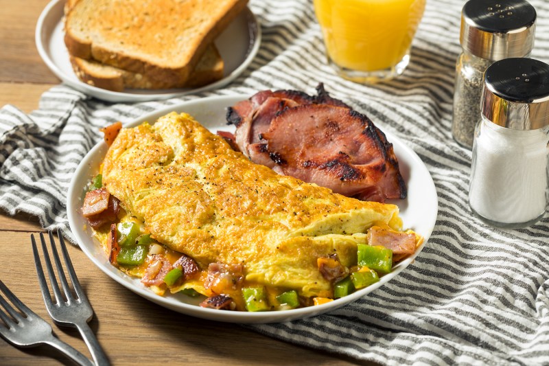 Homemade omelette on plate next to toast and orange juice.