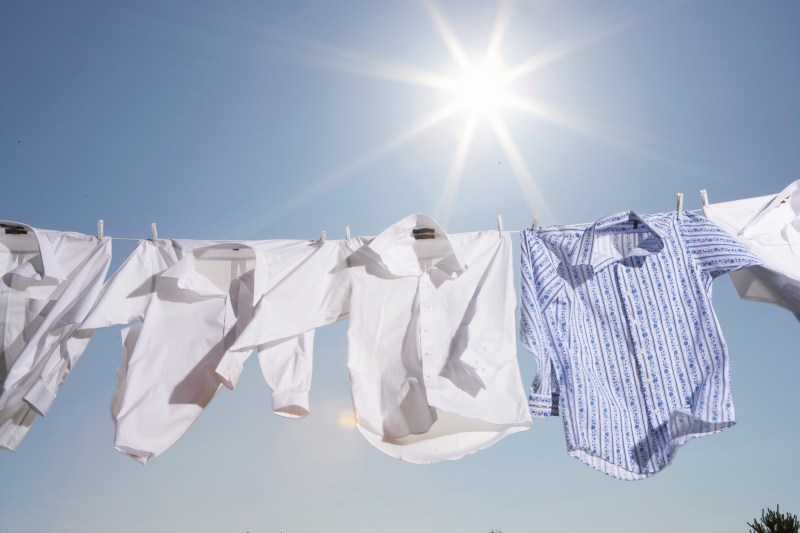 Button down laundries hanging outside under the sun.