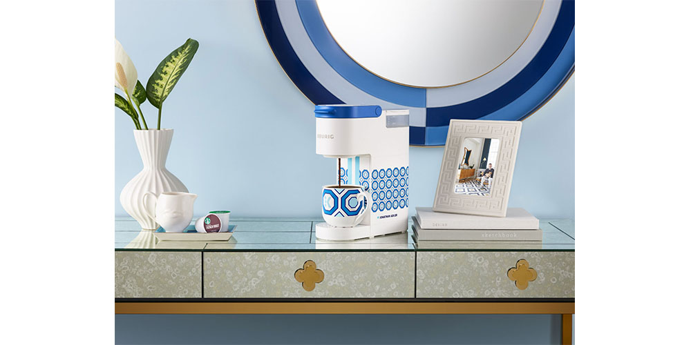 Keurig Jonathan Adler K-Mini Single Serve K-Cup Pod Coffee Maker placed in a home environment on a kitchen top with a blue background.