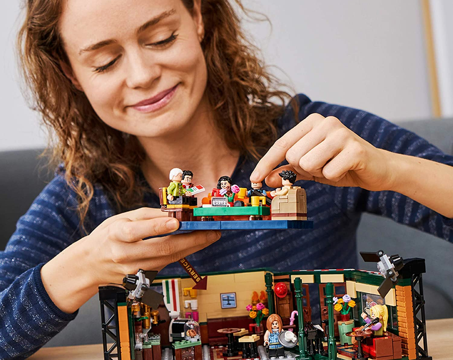Person assembling a LEGO Ideas 21319 Central Perk Building kit.