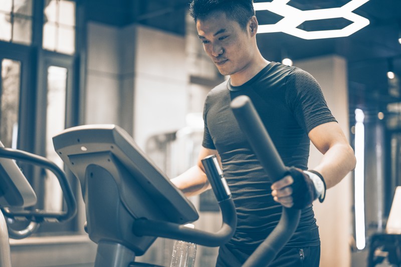 man exercising on a cross trainer in gym.