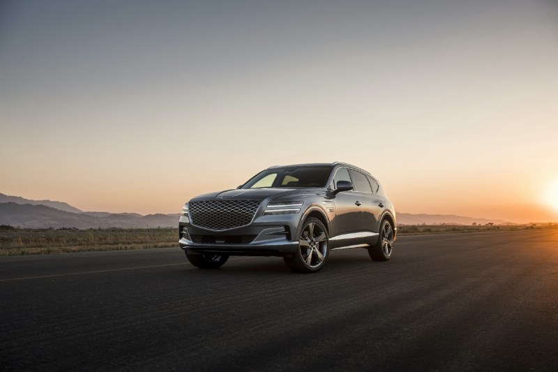 2021 Genesis GV80 on a paved road in front of hill during sunset.