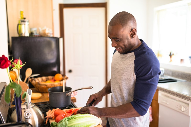 Насмејани човек спрема свој следећи здрав оброк у кухињи.