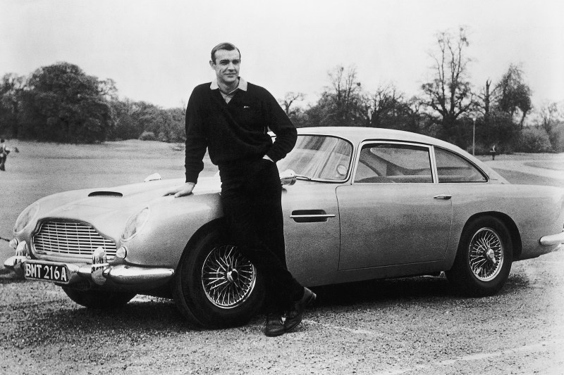 Connery leans on the classic Bond Aston Martin on the set of Goldfinger. 