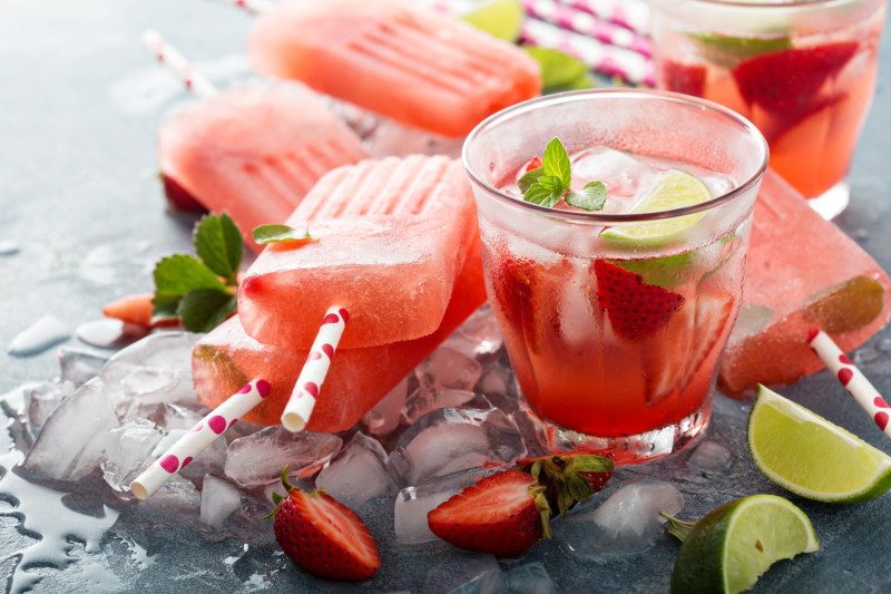 Strawberry mojito popsicles with a glass of it on the side.