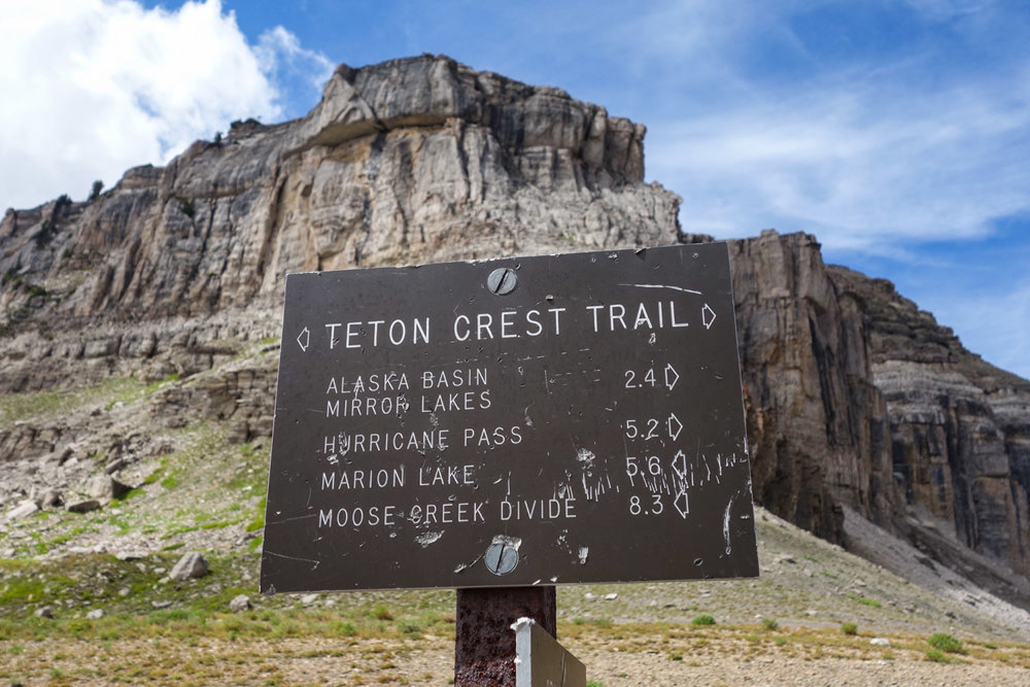 A sign board in Teton Crest Trail that says Alaska Basin, Mirror Lakes, Hurricane Pass, Marion Lake, and Moose Creek Divide.