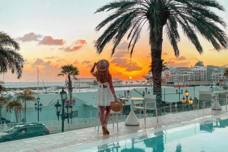 Woman by the pool at sunset at Renaissance Wind Creek Aruba Resort.. 