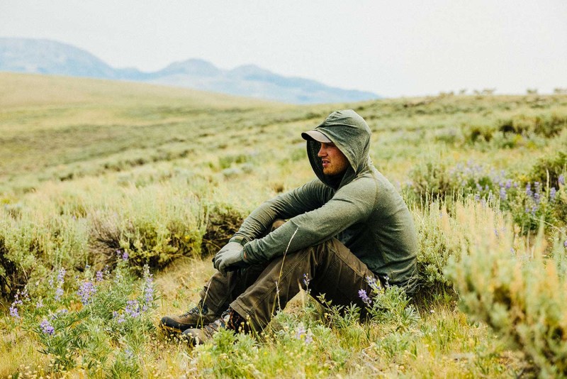 A man sitting in the fields wearing a jacket.