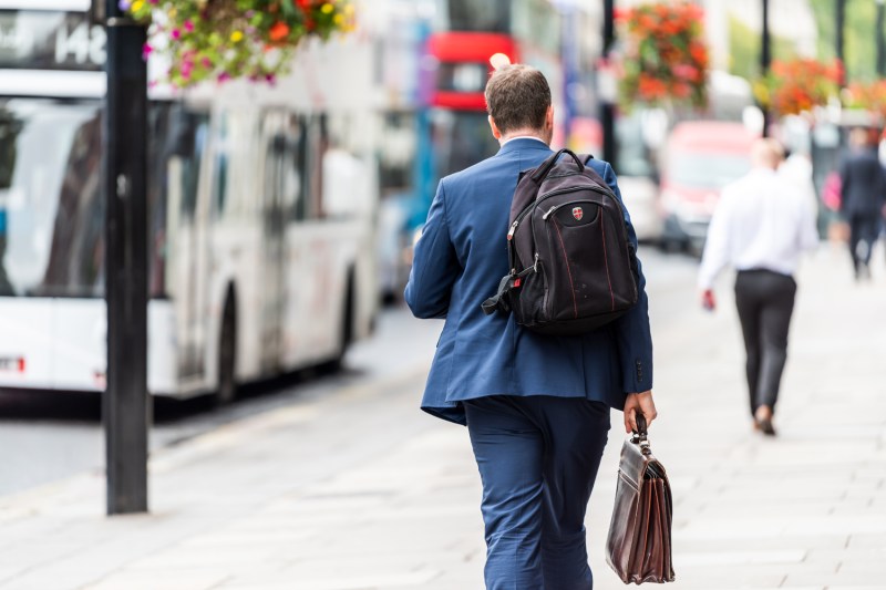 A businessman with backpack and briefcase walking to work.