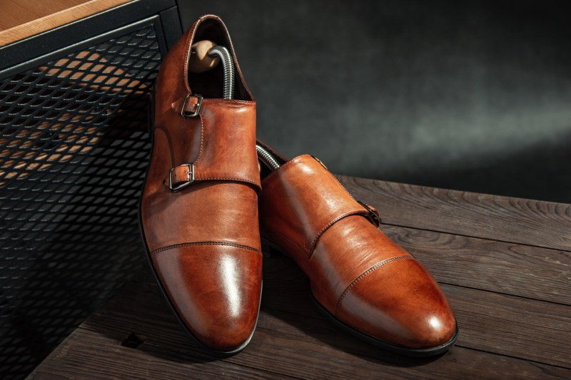 An elegant pair of leather monk strap shoes on a wooden table.