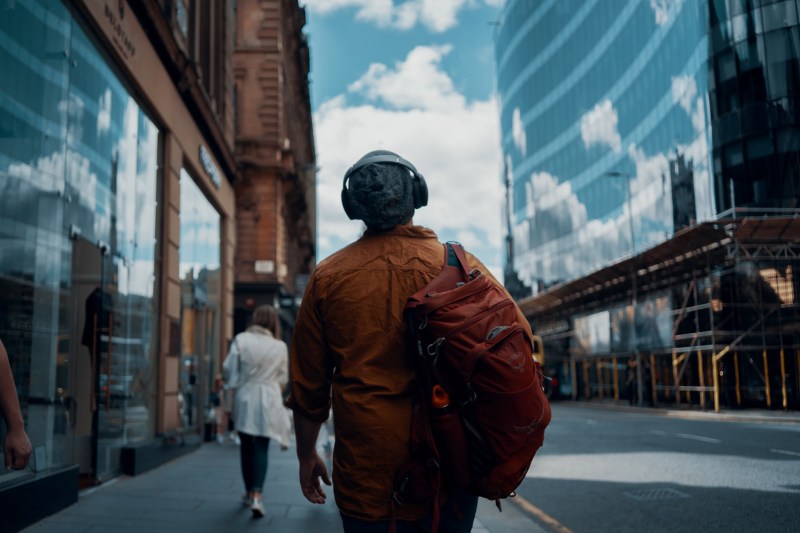 Man walking a city with the best headphones for travel.