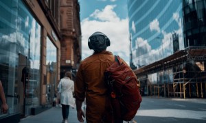 Man walking a city with the best headphones for travel.