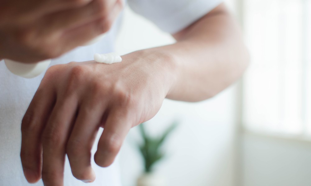 A close-up view of a man applying lotion to his hands.
