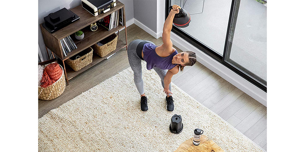 A person using a Bowflex SelectTech Kettlebell in a living room environment.