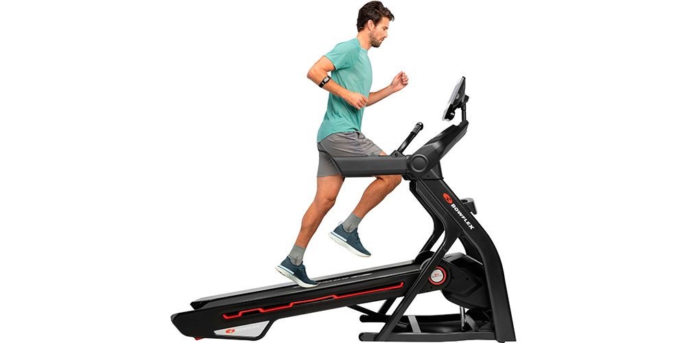A man running on a Bowflex Treadmill 10 with a white background behind him.