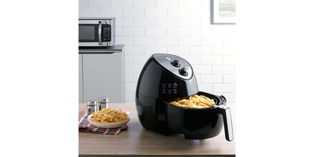 Farberware 3.2 Quart Oil-Less Multi-Functional Air Fryer on a kitchen counter next to a bowl of fries.